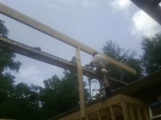 Carpenter setting a ridge beam over a new addition frame — Ice Dam Removal by Roofing Brothers in Ovando