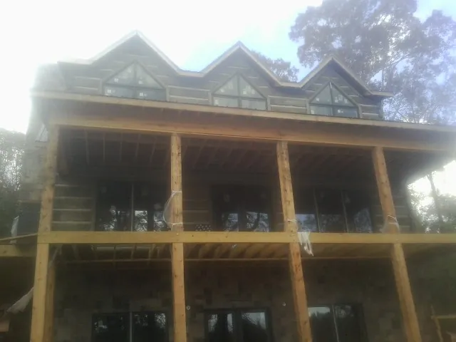 Dormers and porch framing on a large log home under construction — Roof Coating work by our crew in Ovando