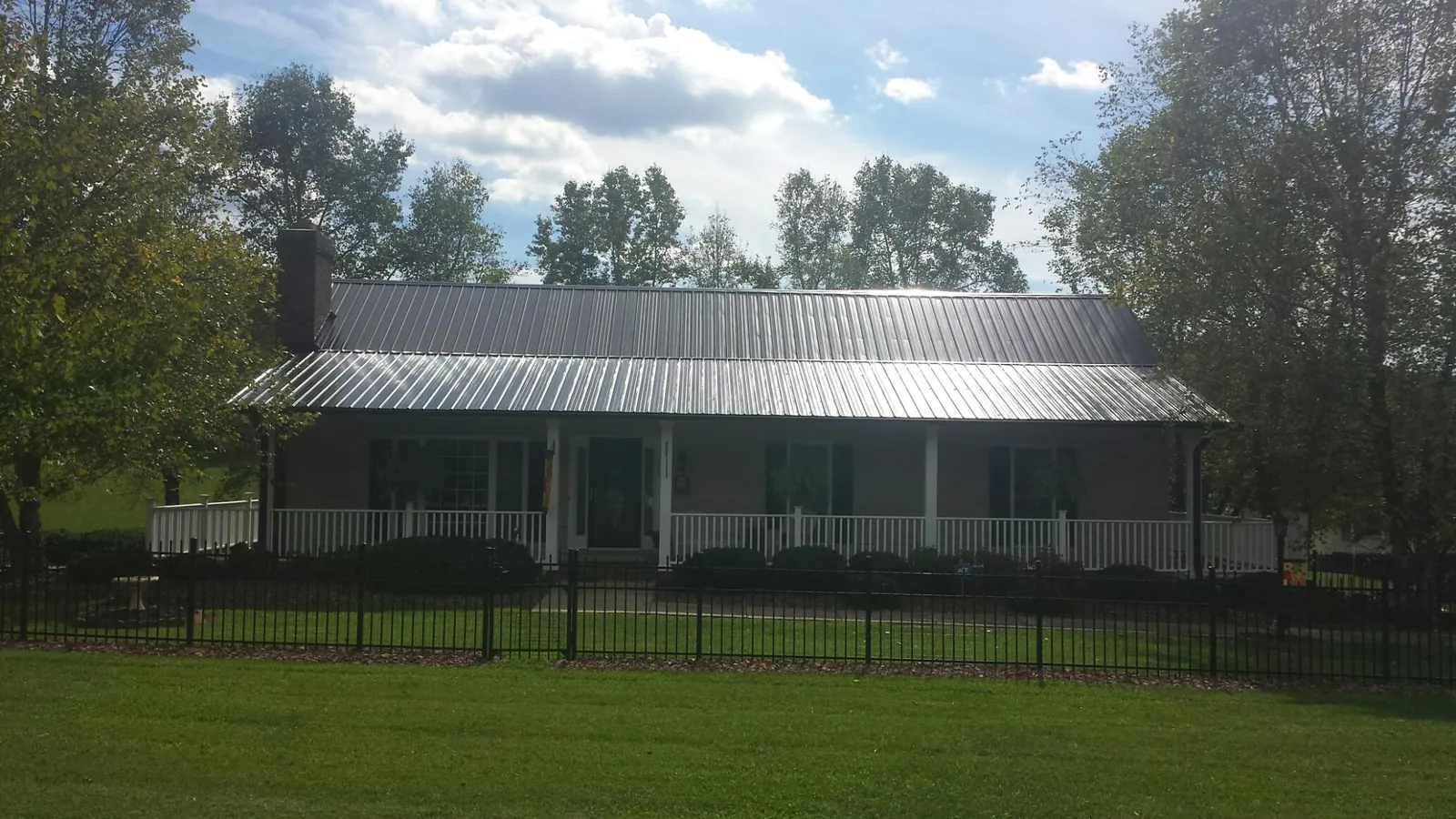 Gray metal roof on a brick ranch with a full width front porch — Gutter Guard Installation work by our crew in Ovando