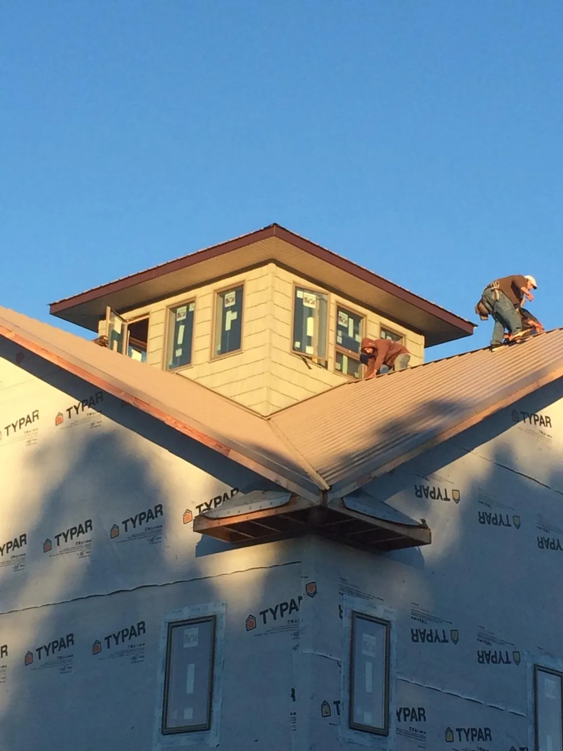 Roofers working around a rooftop cupola on a new metal roof at sunset — Roof Waterproofing in Ovando by Roofing Brothers
